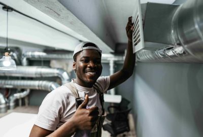 young-man-smiles-gives-thumbs-up-while-hanging-notice-modern-office-space-daytime_11zon